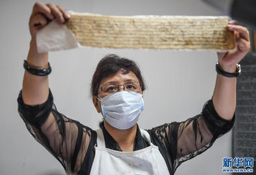 央拉正在检查一叶修复中的濒危藏文古籍