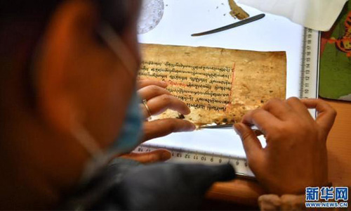 央拉正在修复一叶濒危藏文古籍